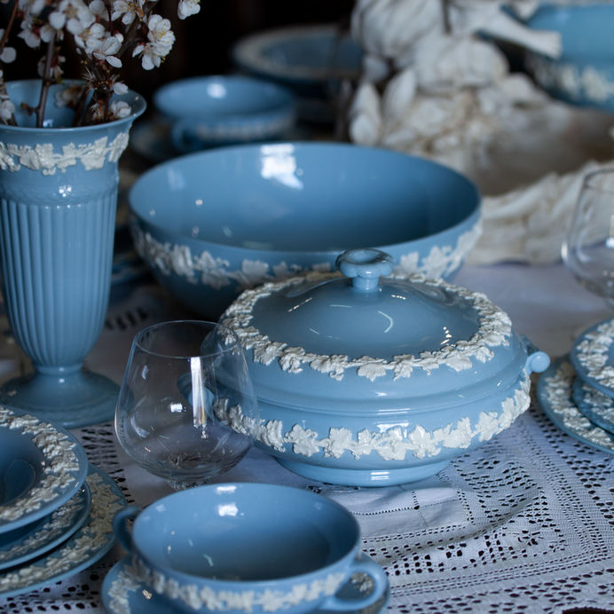 an antique blue teas et and fine China set on a table with a lace tablecloth